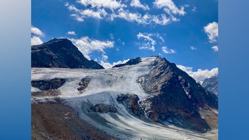 A large snow covered mountain with a plane flying overhead.