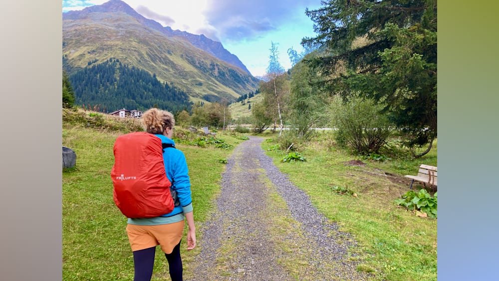 A woman wearing a blue jacket is walking down a path in the woods.