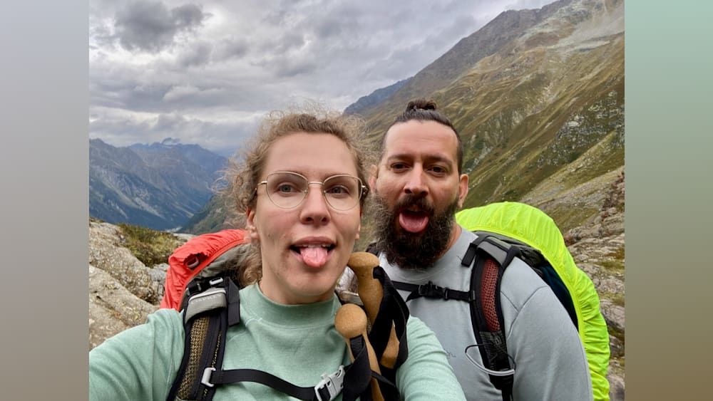 A woman with glasses and a man with a beard on a mountain.