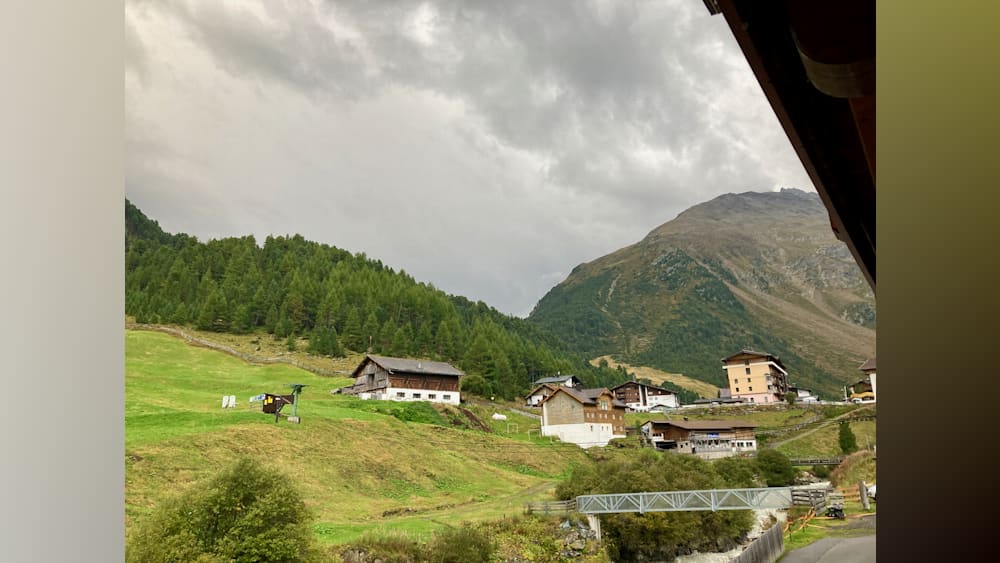 A view of a small mountain community with a bridge and buildings in the background.