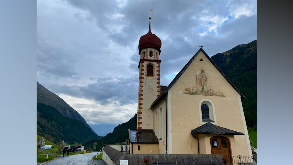 A church with a steeple and a tower that is very cloudy.
