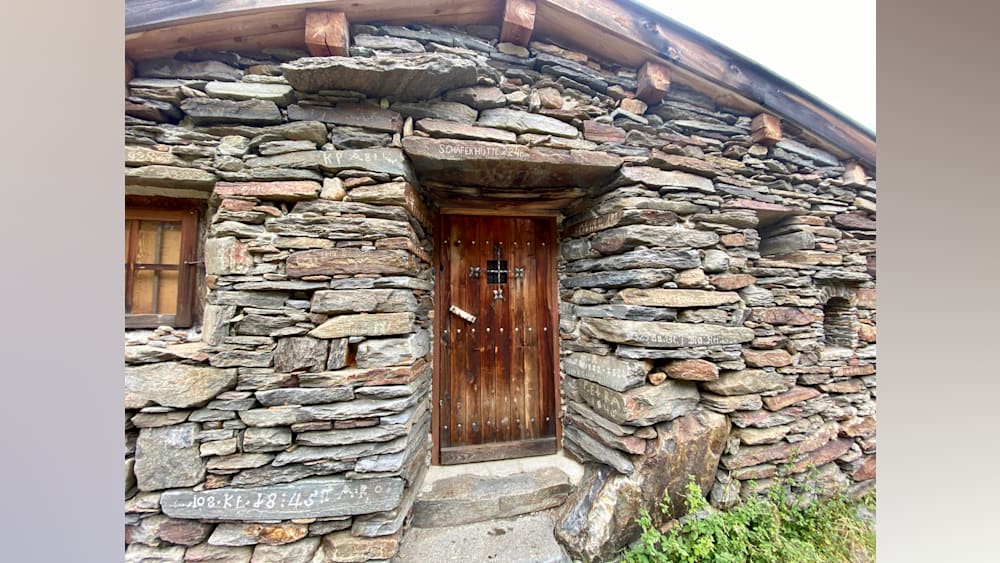 A stone building with a wooden door and a cross on the door.