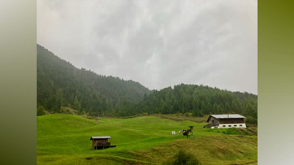 A hilly area with a green field and a building in the background.