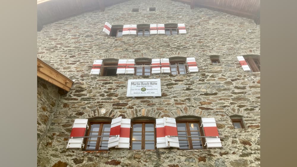 The shutters on the building are red and white and they are on the windows.