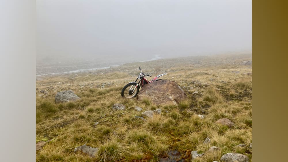 A motorcycle is sitting on a rock in a field.