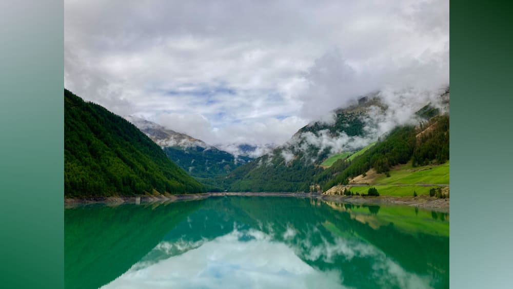 A lake is surrounded by mountains and the water is a deep blue.