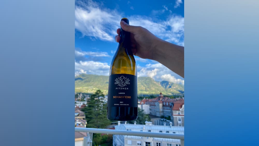 A bottle of Pitzner Lagrangeisch has been held up in front of a mountain range.
