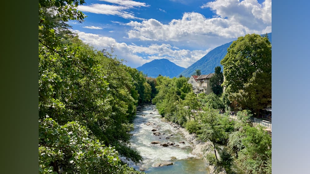 A river flows through a town with houses and trees nearby.
