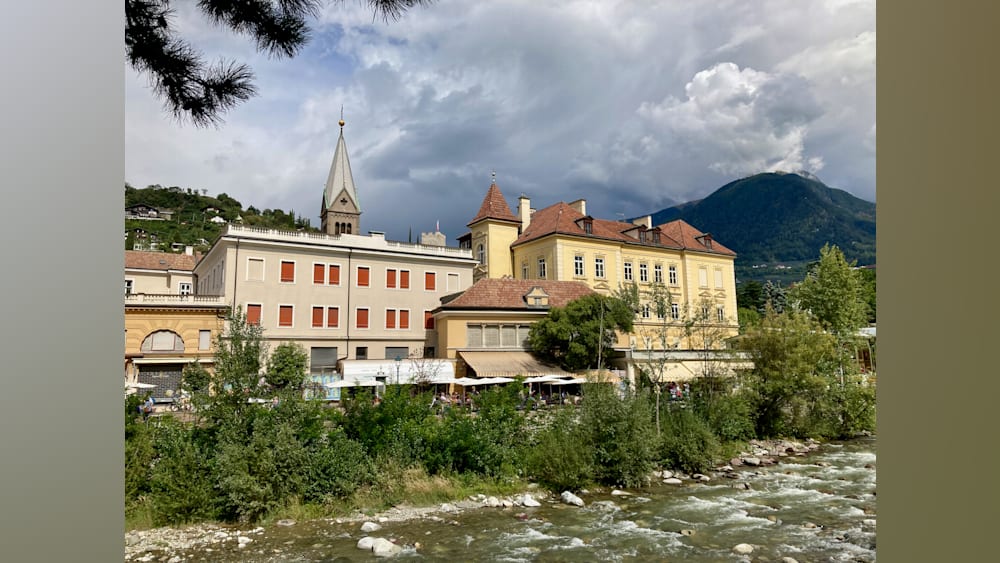 A river runs next to a building and a church steeple.
