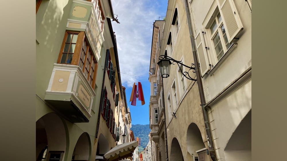 A street with a banner on a wire between two buildings.