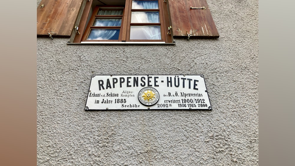 A sign that says "Rappenssee-Hutte" is on the side of a building.