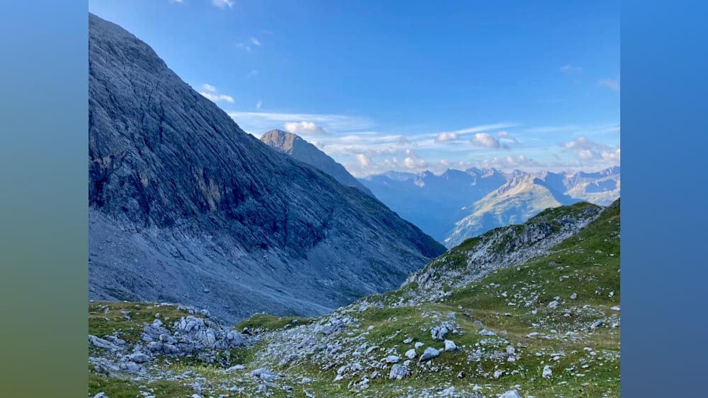 A mountain with a valley and a blue sky in the background.