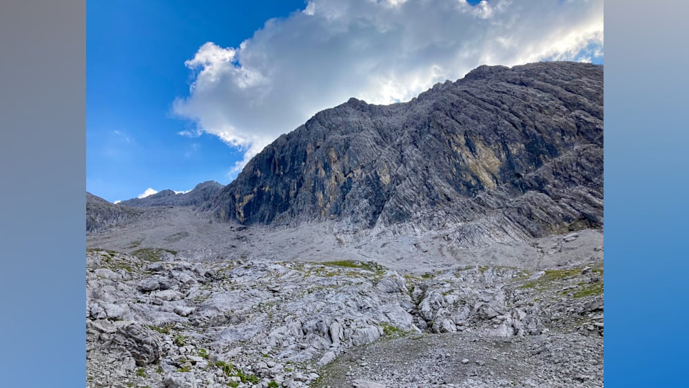 A large grey rock face with a blue sky in the background.