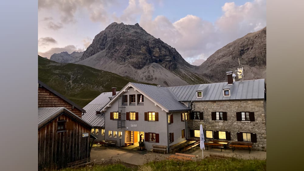 A building with many windows sits in front of a mountain.