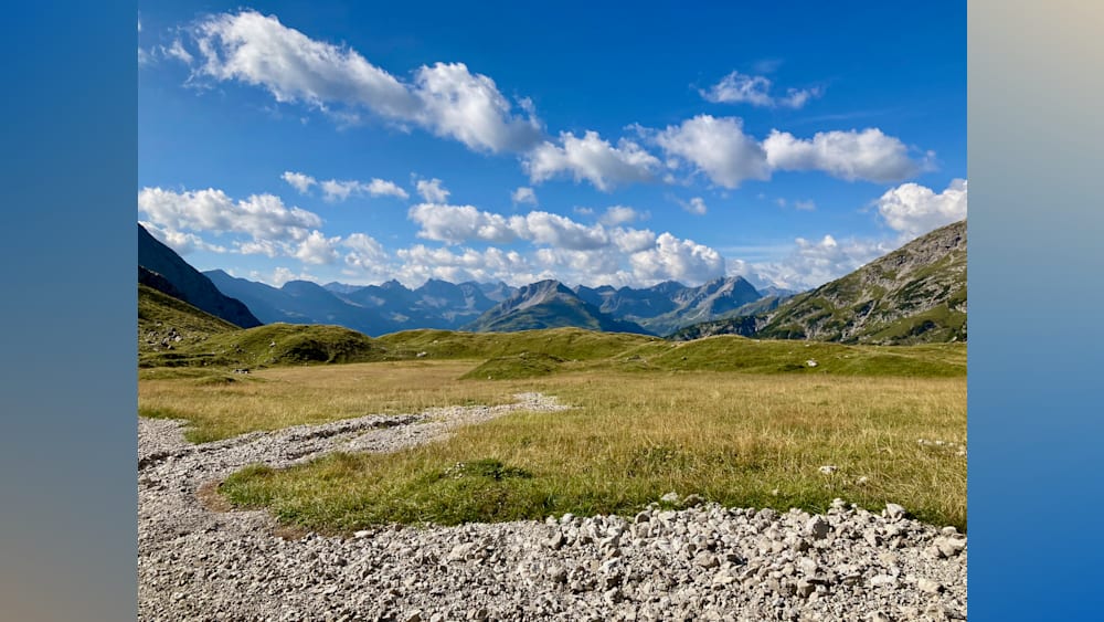 A large open field with grass and mountains in the distance.