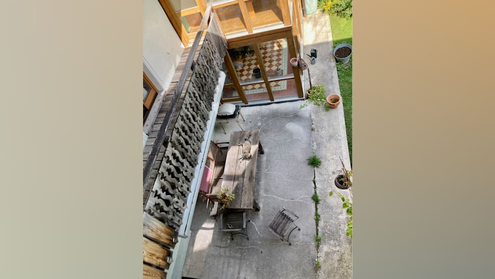 An outside area with a table and chairs and potted plants.