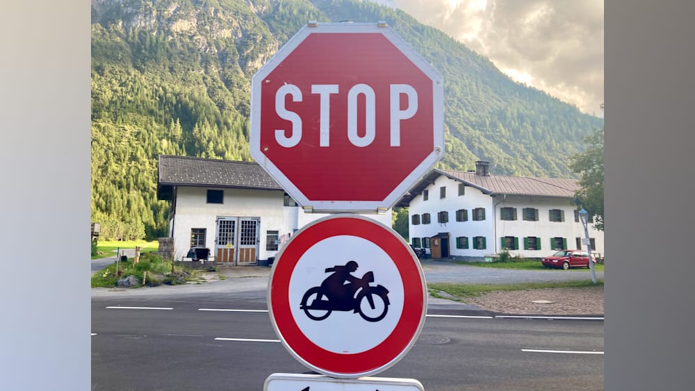 Stop sign on the side of the road that is in front of a white building.