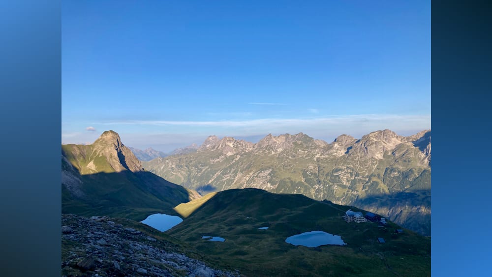 A mountain with a blue lake in it and the mountain range in the background.