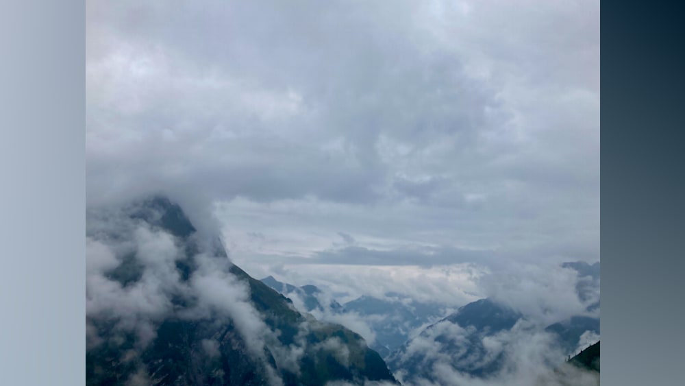 A foggy mountain peak with clouds and a valley below.
