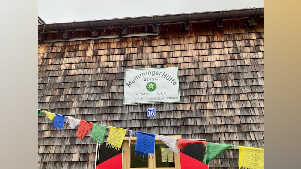 A sign that saysMemminger Hutte in blue on a building.