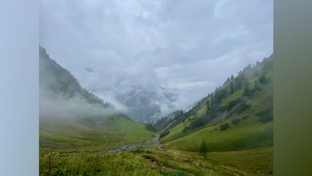 A foggy mountain range with a stream running through it.