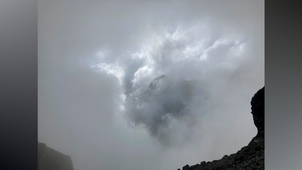 A large cloud that looks like a dragon is in front of a mountain range.