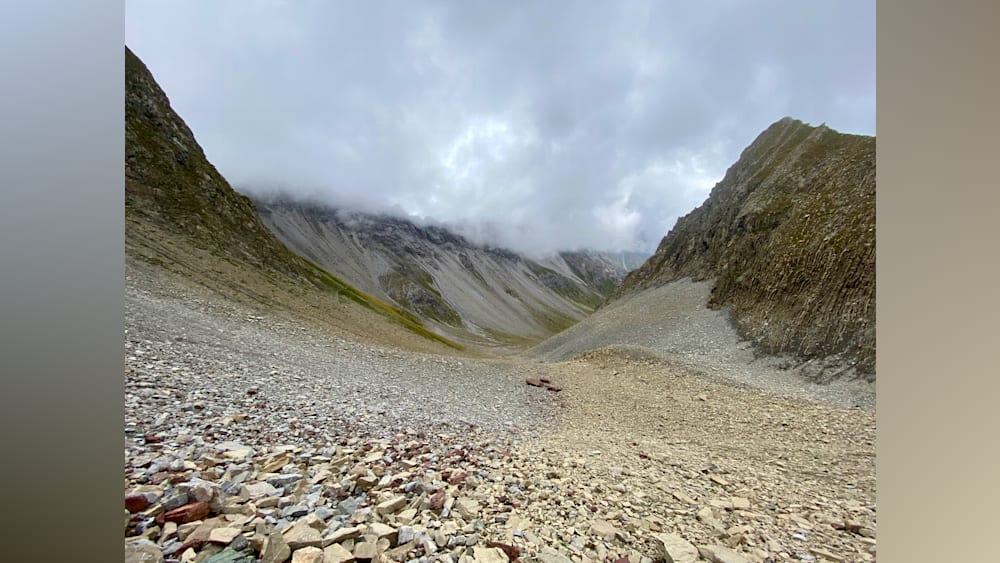 A rocky mountain pass with a lot of gravel and a lot of clouds.