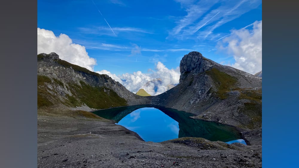 A large lake with a mountain in the background and a large body of water reflecting the sky.