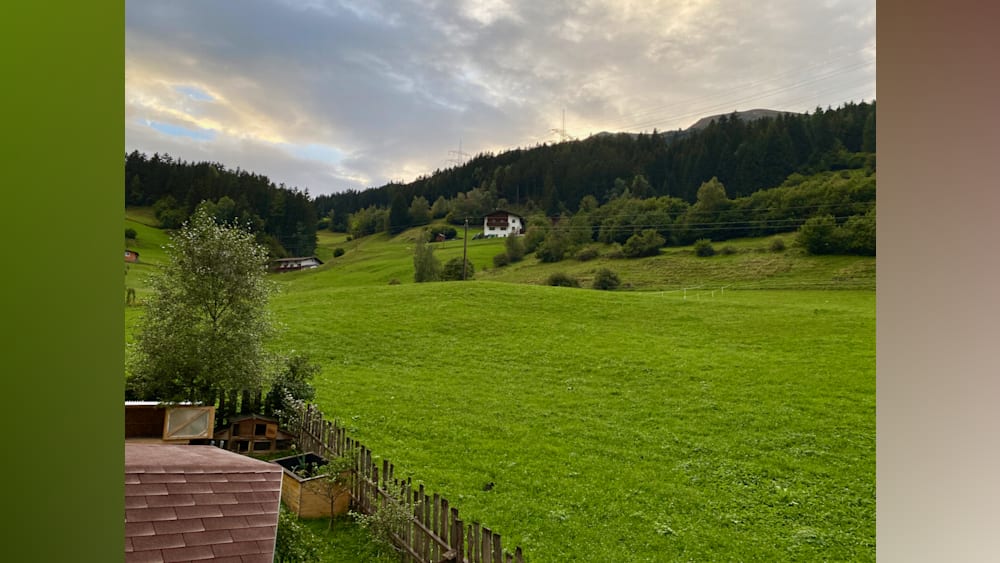 A fenced in field with a house in the background.