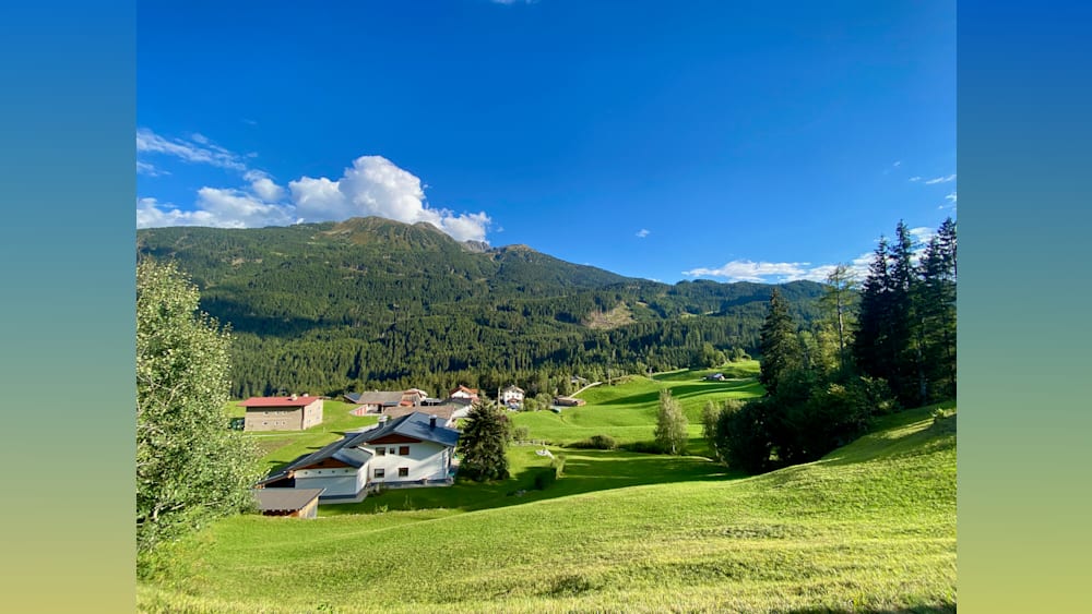 A house with a white roof is sitting on a green hillside.