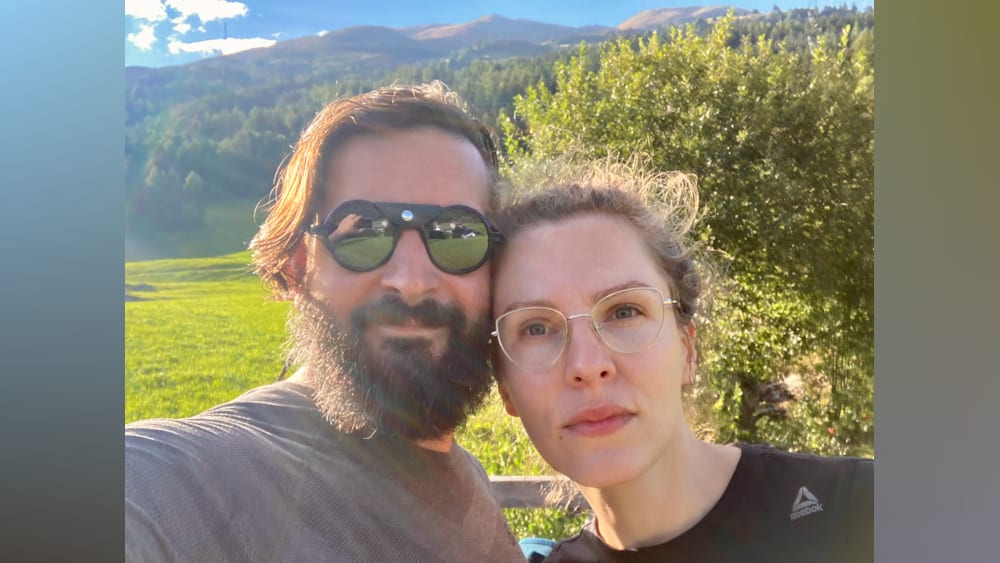 A man and a woman wearing glasses are standing next to each other.