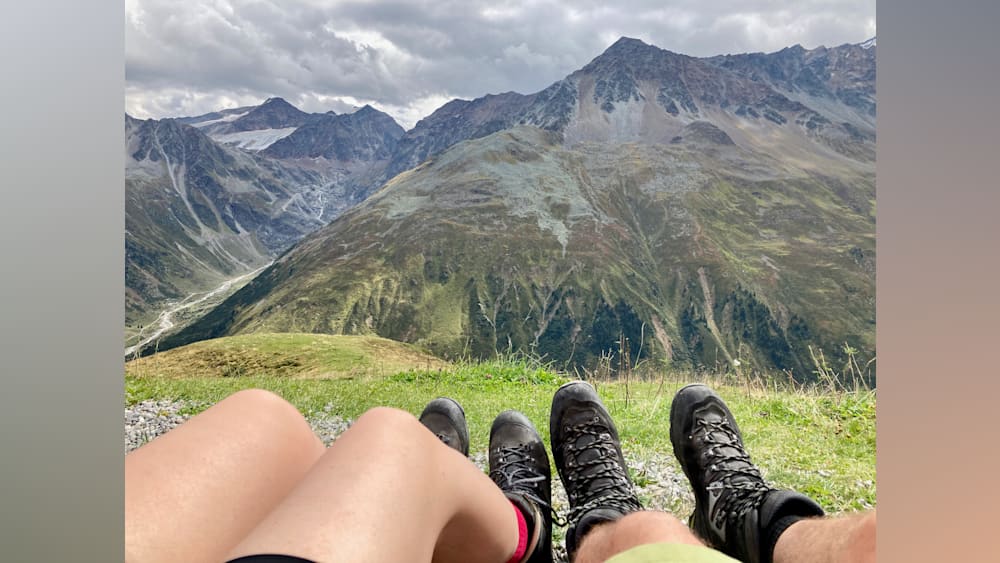 Two people sitting next to each other with their feet on the grass.