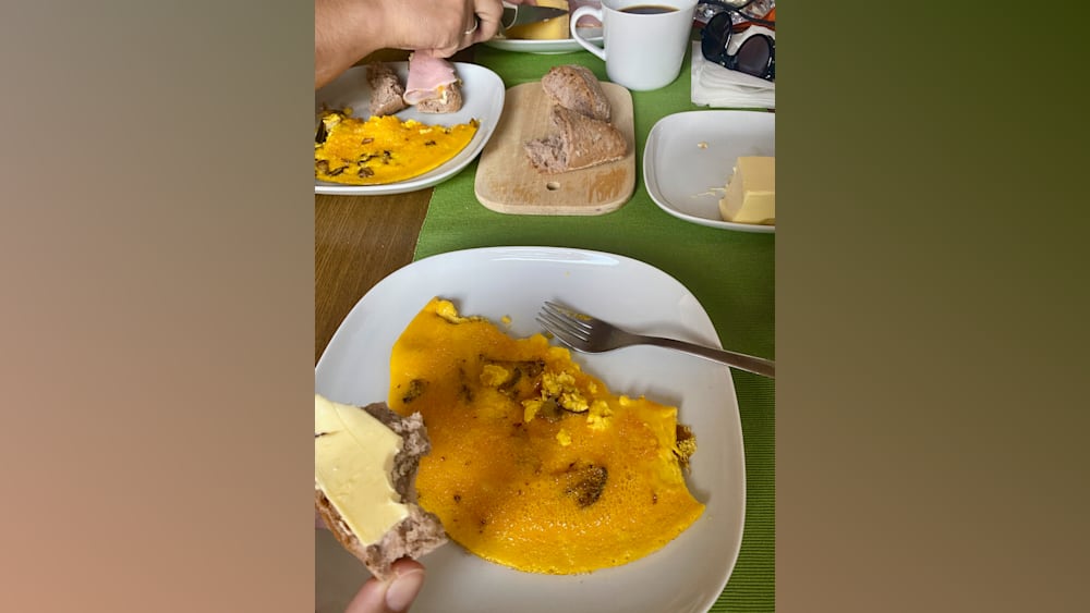 A plate of food with a fork on a table with a green placemat underneath.