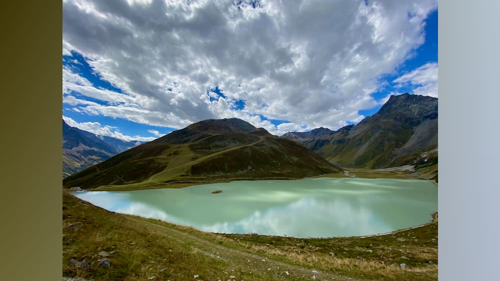 A lake is surrounded by mountains and the water is a light blue color.