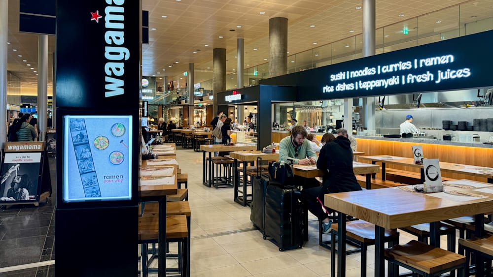 People in a restaurant with luggage in front of them.