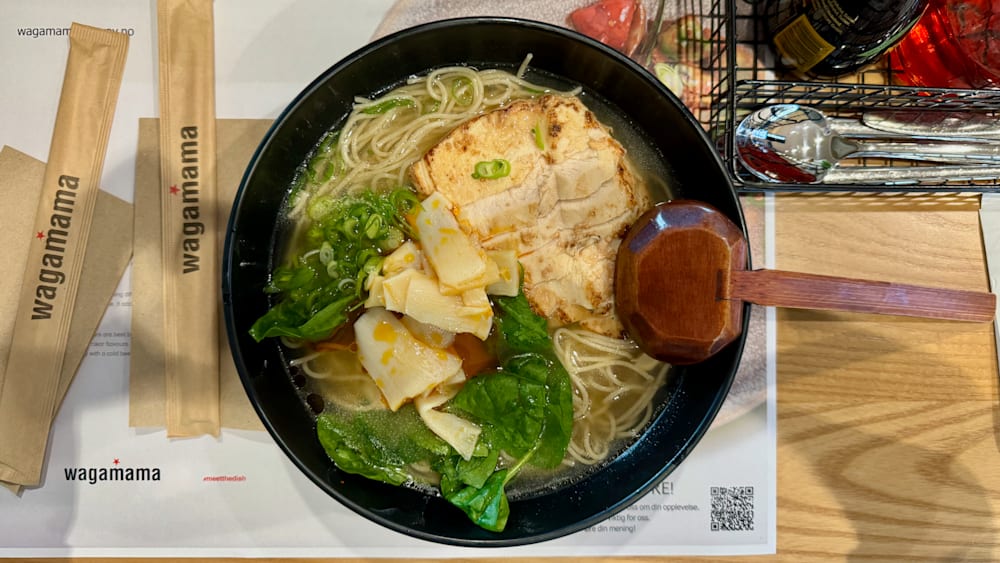 A noodle dish with vegetables such as spinach and onions served in a bowl.