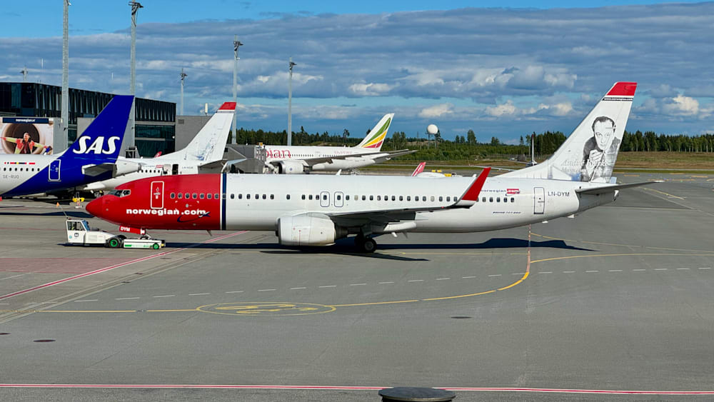 A red and white airplane with the number 0 on it is parked on the runway.