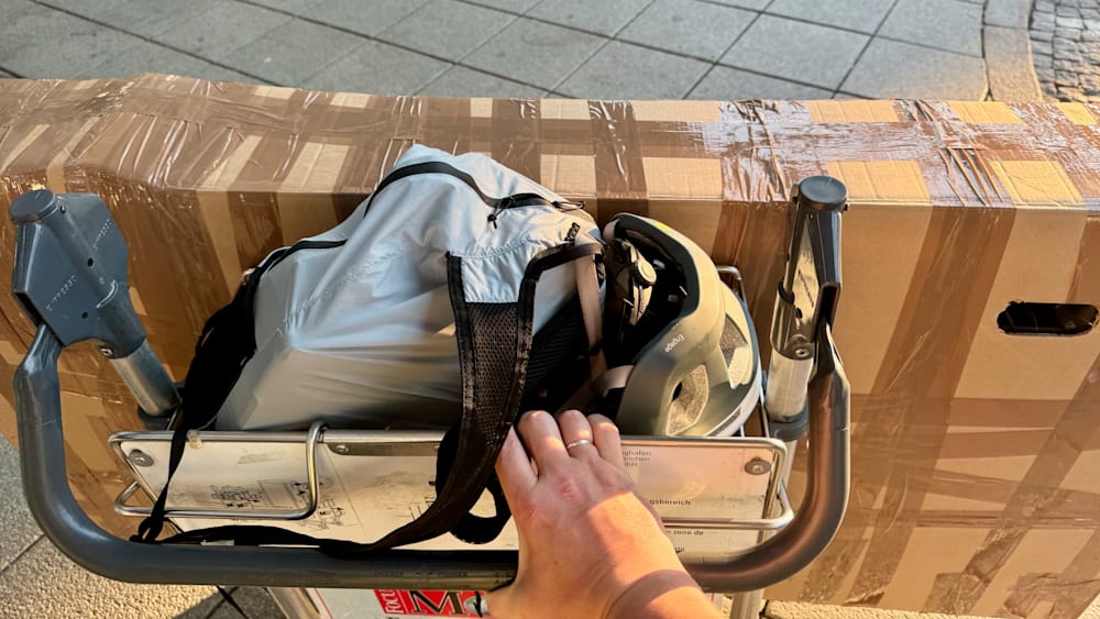 A person is holding onto a piece of luggage with a helmet in it.