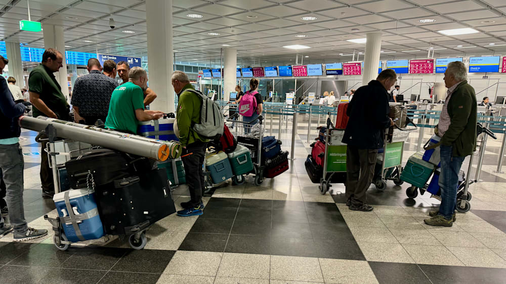 People are waiting in line at an airport with their luggage.