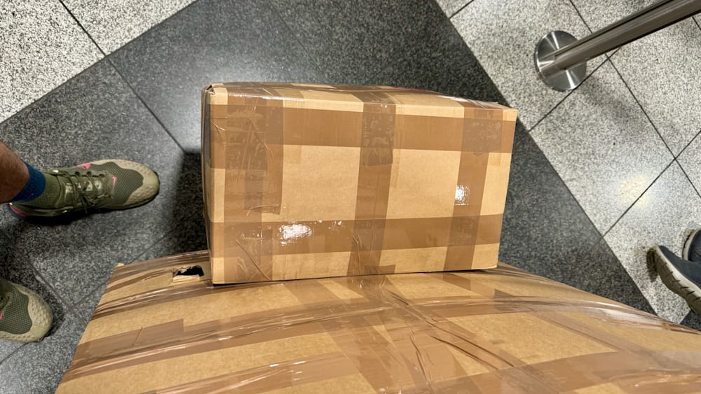 A box covered in duct tape lies on its side on a gray floor.