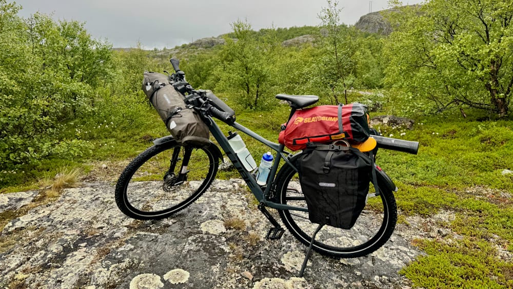 A mountain bike with a black bag on it with the words Bear Grylls on it.