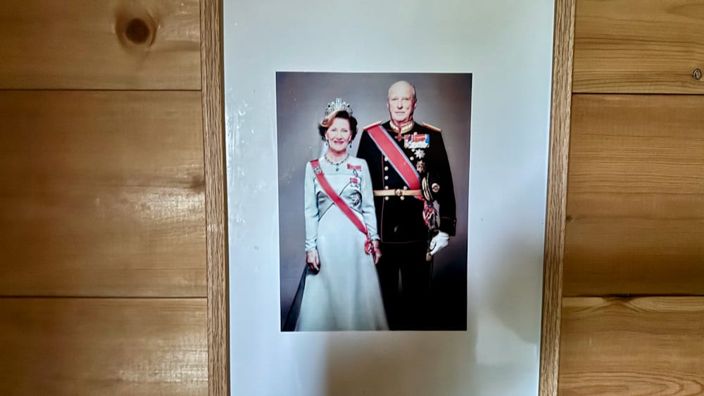 A picture of a man and woman with military uniforms with a large red sash with a bow and a flag.
