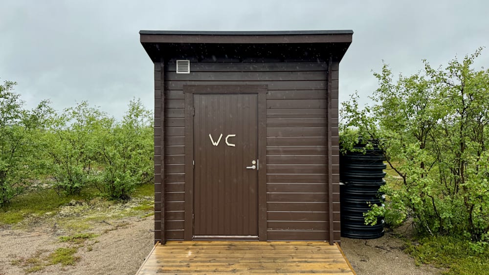 A small wooden building has a sign on it that says "WC".