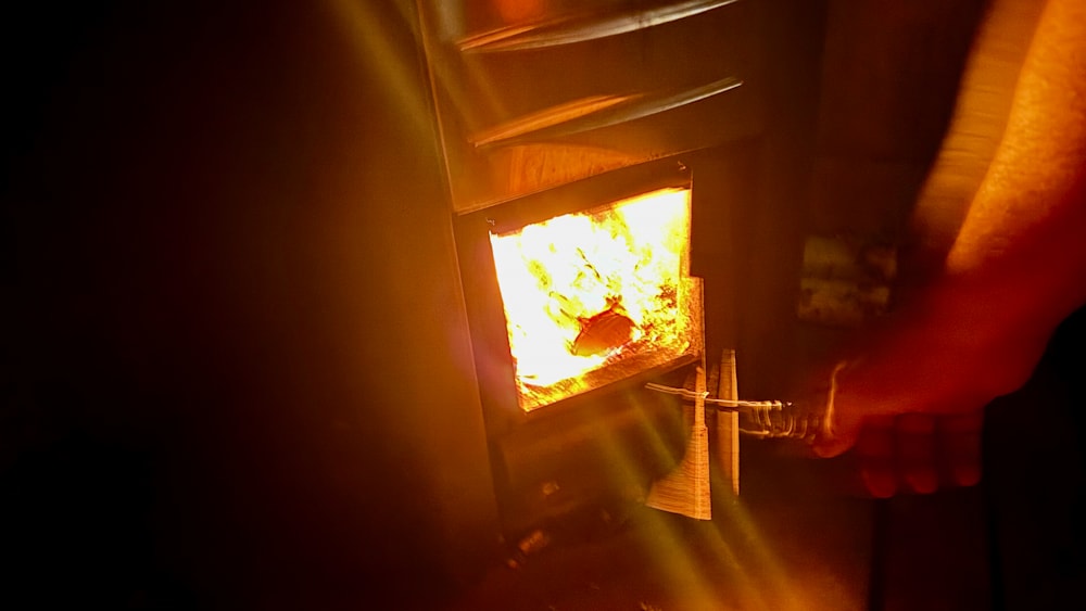 A person is pulling out a match from a fire place that is already lit.