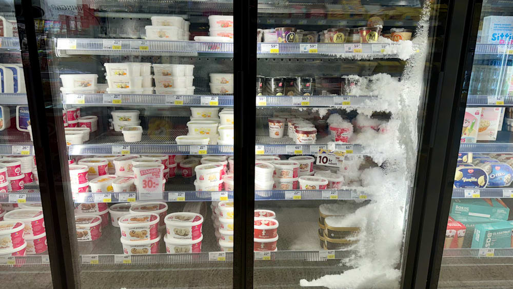 A lot of yogurt is sold in a store with a lot of ice cream on display as well.
