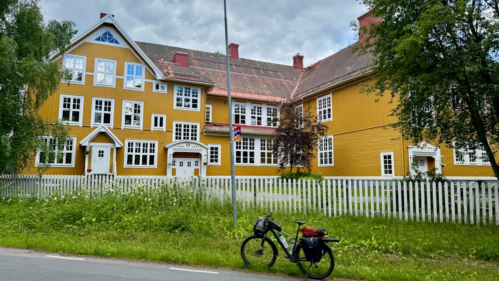 A bicycle is parked in front of a yellow building.