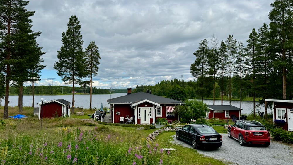 A black car is parked in front of a red house.