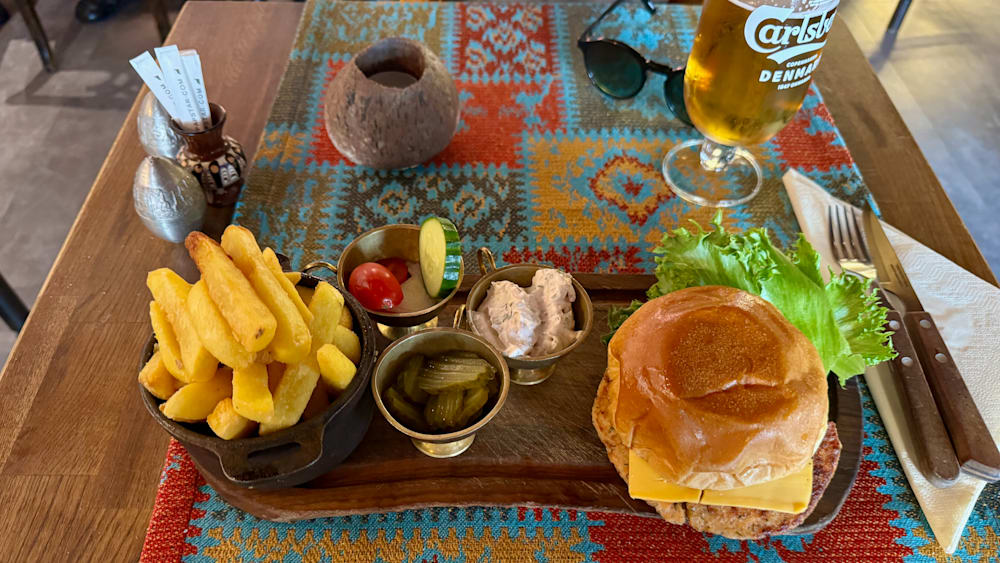 A plate of food with a hamburger and fries with various condiments.