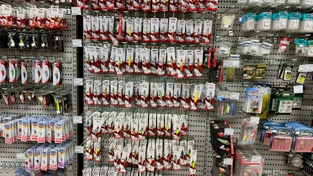 A row of fishing lures are displayed on a wall in a store.