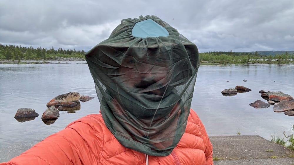 A man is wearing a green net across his face.